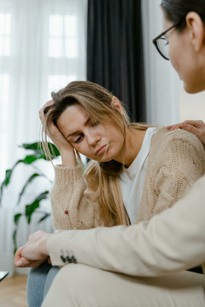 A worried woman being comforted by a friend indoors. Shows empathy and support.